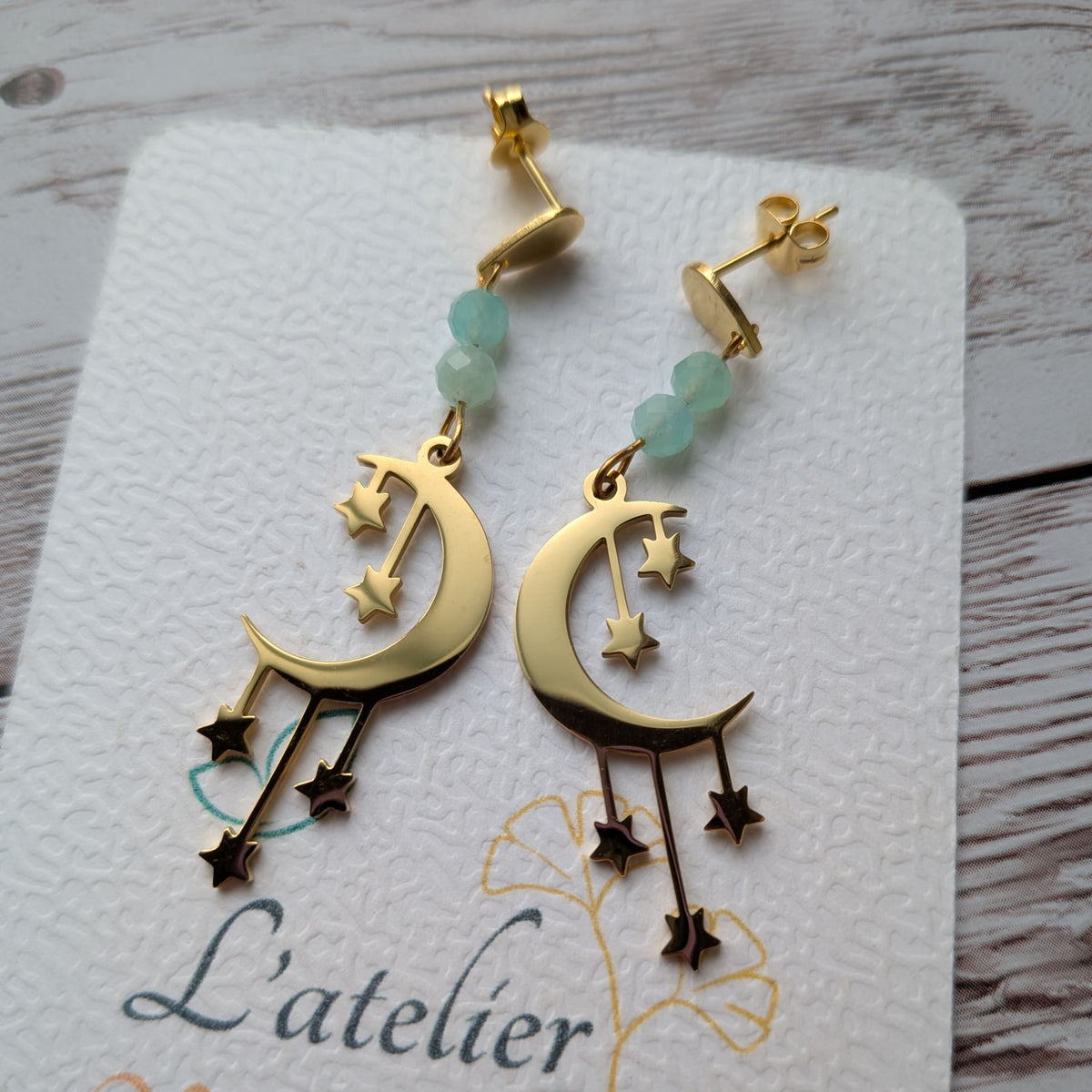 Gros plan détaillé des boucles d'oreilles lune et étoiles dorées sur support.
