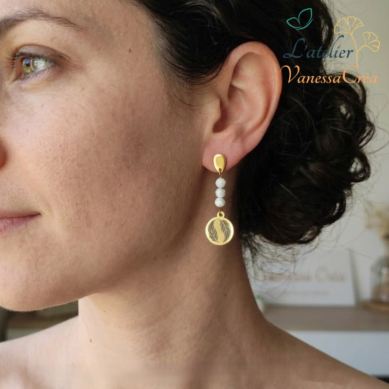 Vue de profil d'une femme portant des boucles d'oreilles pendantes motif plume avec perles naturelles.