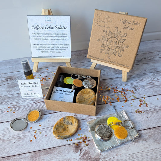 Vue d'ensemble du coffret lithothérapie et aromathérapie Éclat Solaire, avec son parfum bio, son galet d'agate crazy lace et son porte-clés soleil sur fond de bois.
