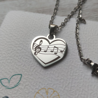 Collier pendentif cœur en acier inoxydable avec gravure de partition et notes de musique, finition poli miroir.