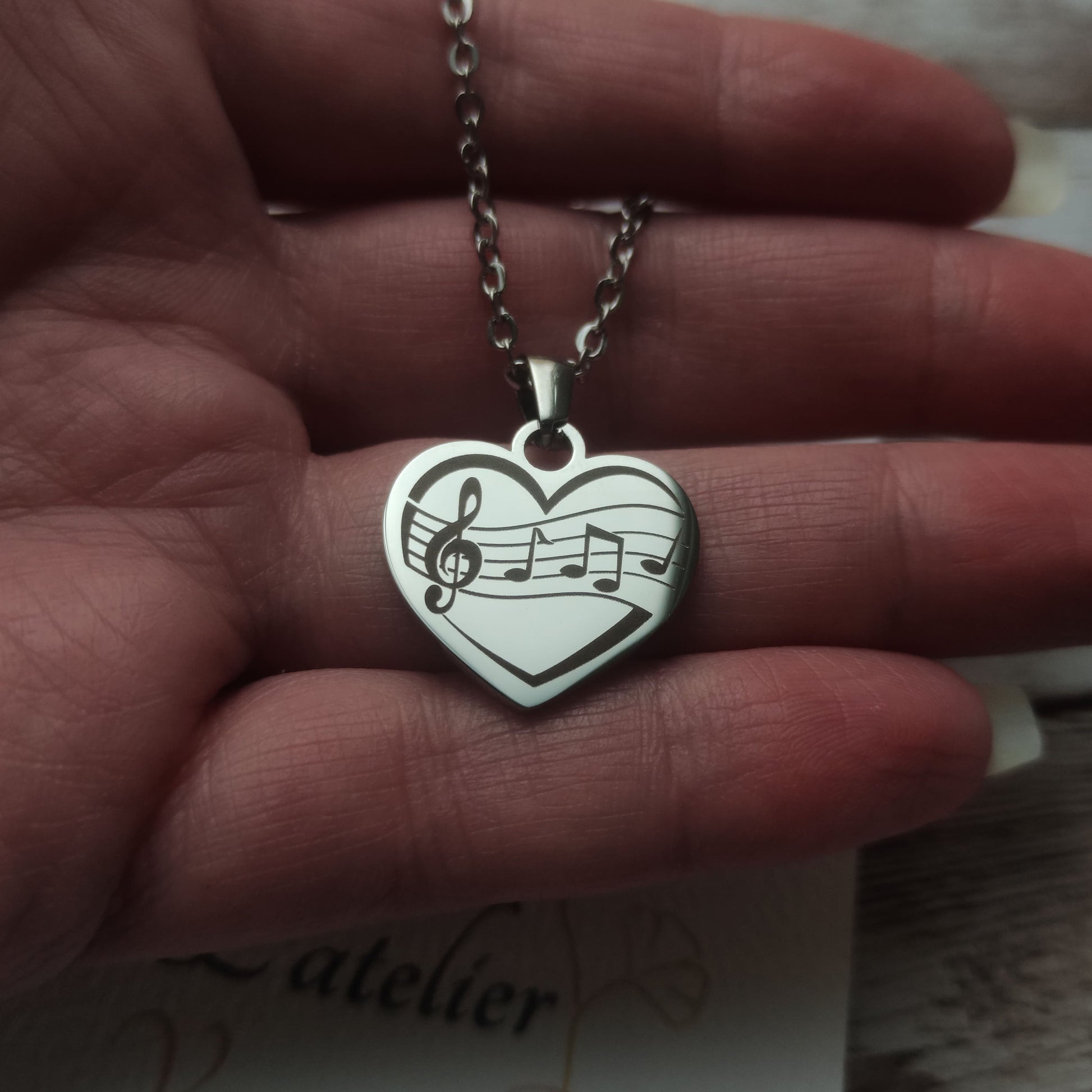 Collier pendentif cœur en acier inoxydable argenté avec gravure de partition et notes de musique, finition poli miroir.
