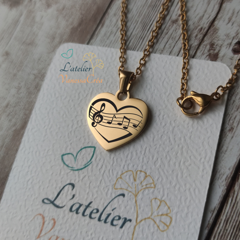 Collier pendentif cœur en acier inoxydable doré avec gravure de partition et notes de musique, finition poli miroir.