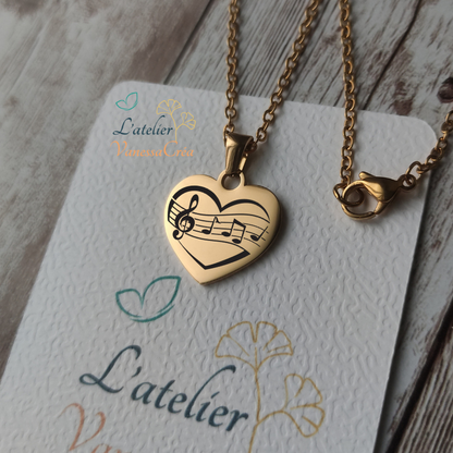 Collier pendentif cœur en acier inoxydable doré avec gravure de partition et notes de musique, finition poli miroir.