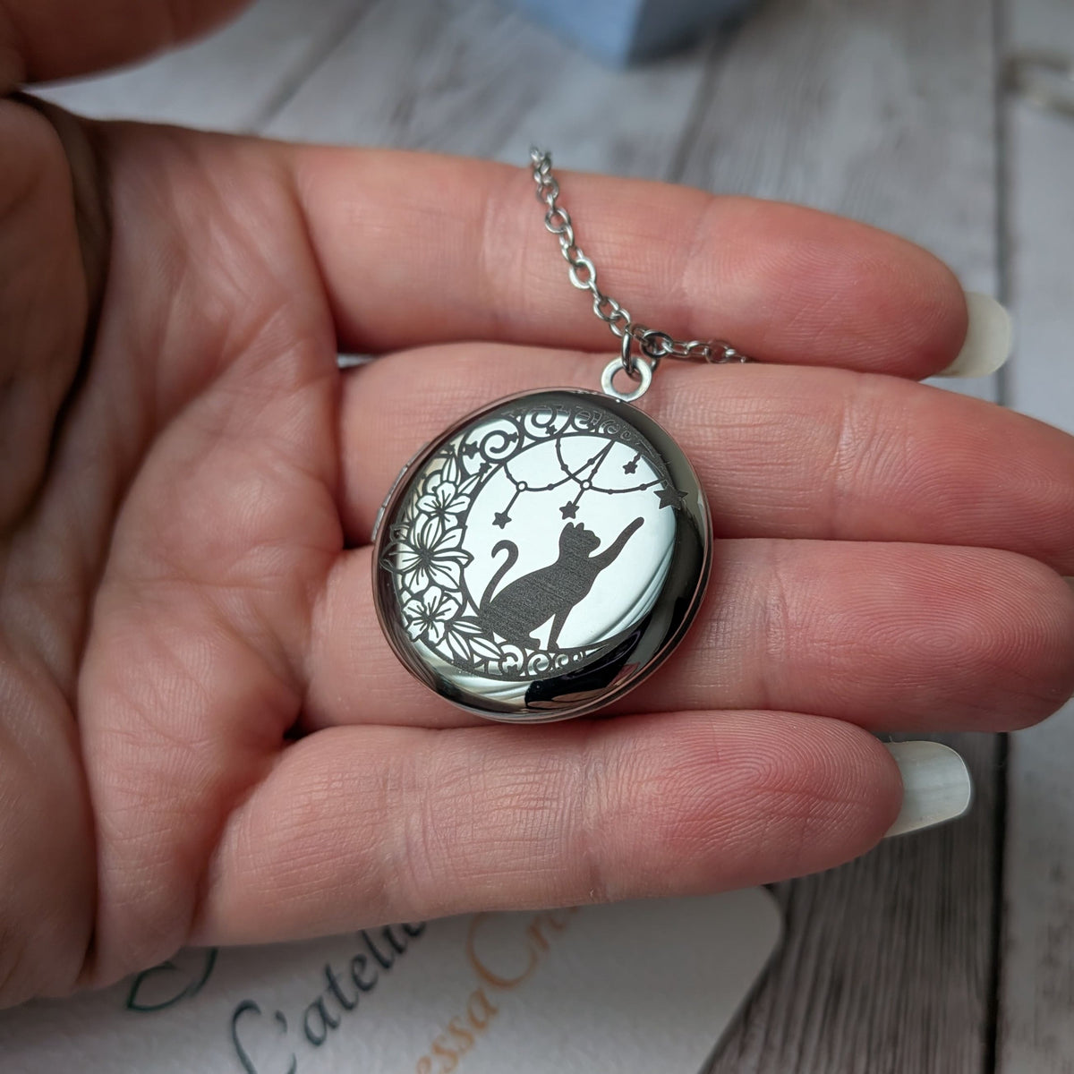 Collier diffuseur d'huiles essentielles Chat et Étoiles argenté présenté dans la main