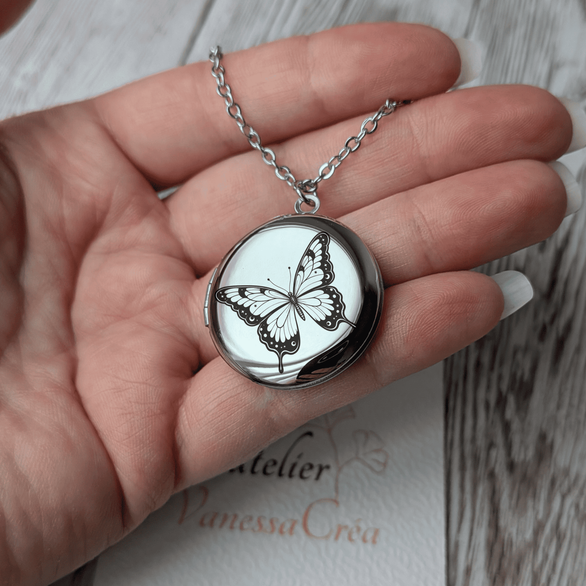 Collier diffuseur d'huiles essentielles gravure Papillon présenté dans la main