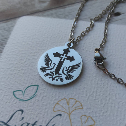 Pendentif rond poli miroir en acier inoxydable avec gravure de précision d'une croix entourée de deux colombes.