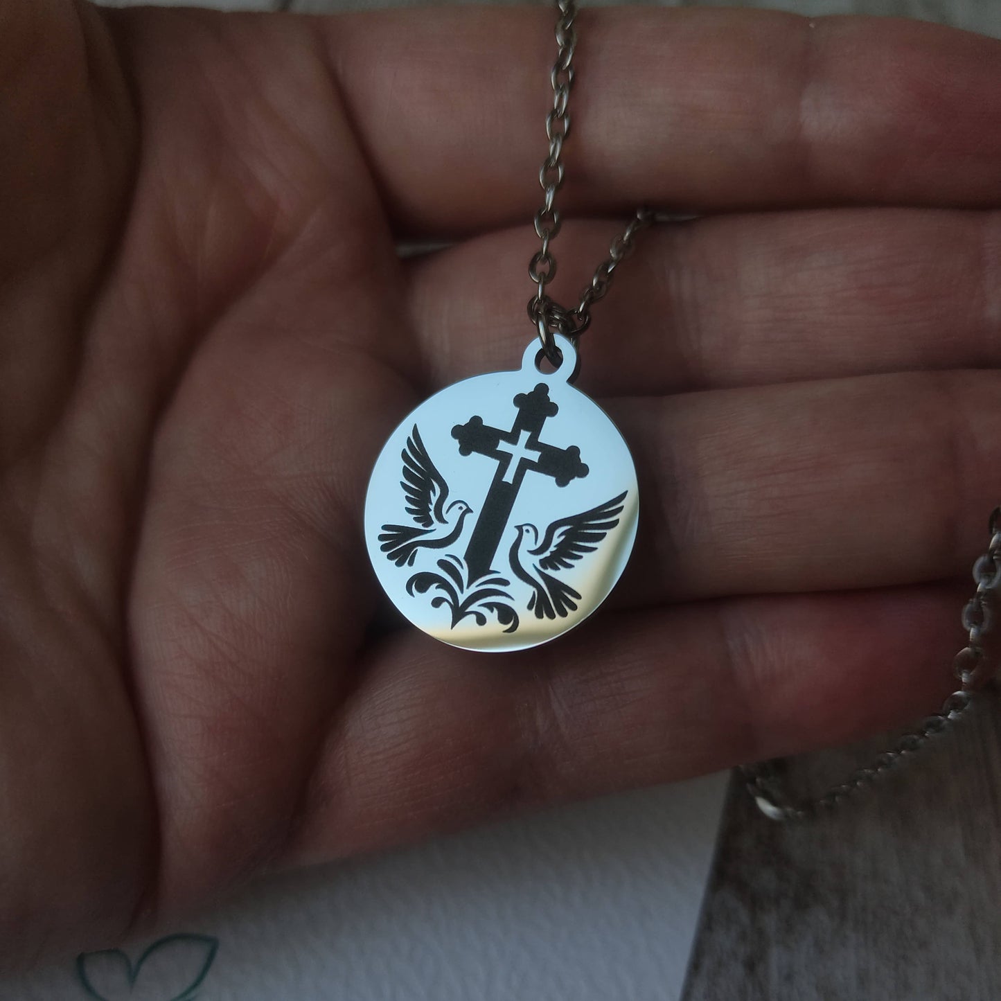 Pendentif rond poli miroir en acier inoxydable avec gravure de précision d'une croix entourée de deux colombes.