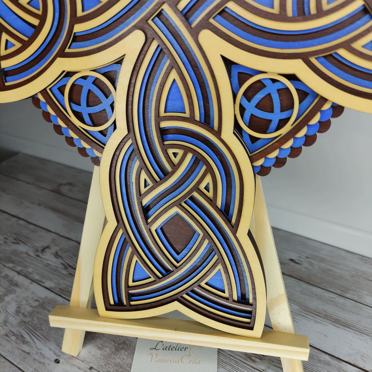 Vue de trois-quarts d'une croix celtique en bois, mettant en valeur son relief et ses détails peints en bleu.