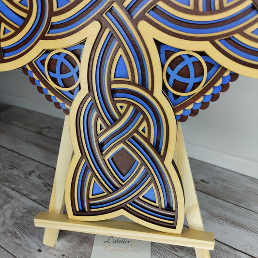 Vue de trois-quarts d'une croix celtique en bois, mettant en valeur son relief et ses détails peints en bleu.