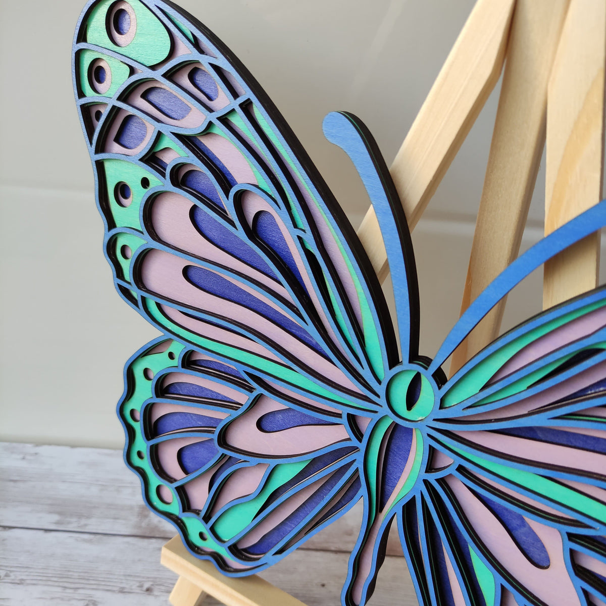 Gros plan sur les détails et les couleurs des ailes du papillon en bois, mettant en valeur la précision de la découpe.
