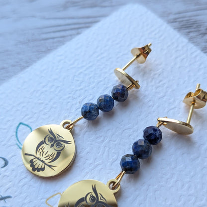 Gros plan sur le médaillon gravé motif chouette et les perles bleues des boucles d'oreilles artisanales Vanessa Créa.