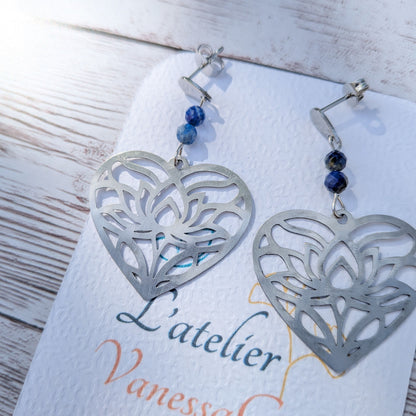 Gros plan sur les finitions des boucles d'oreilles cœur ajouré en acier et les perles facettées de lapis-lazuli.