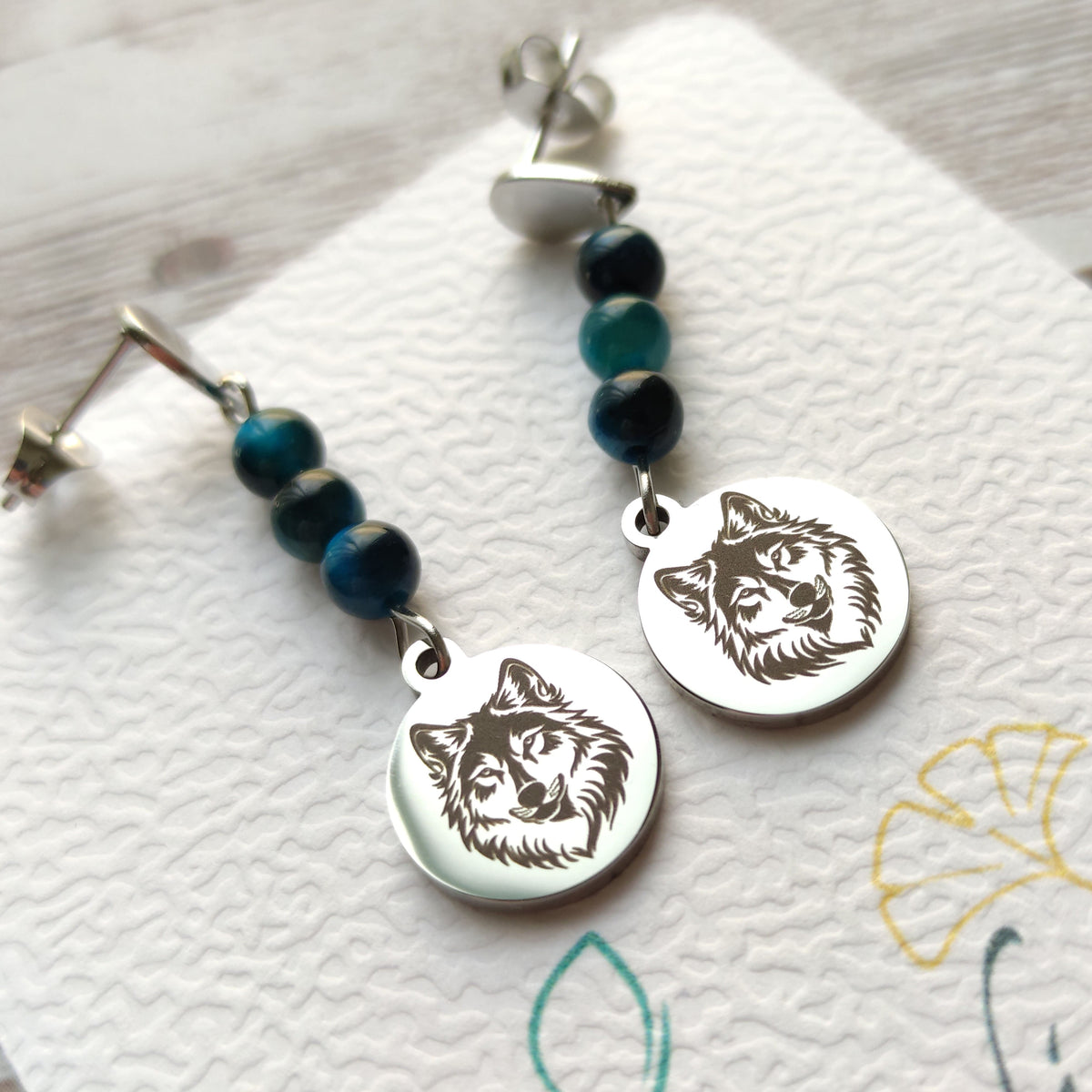 Gros plan sur le médaillon gravé motif loup des boucles d'oreilles artisanales Vanessa Créa.