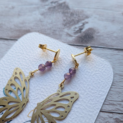 Détail des attaches et des finitions polies des boucles d'oreilles papillon artisanales en laiton protégé.