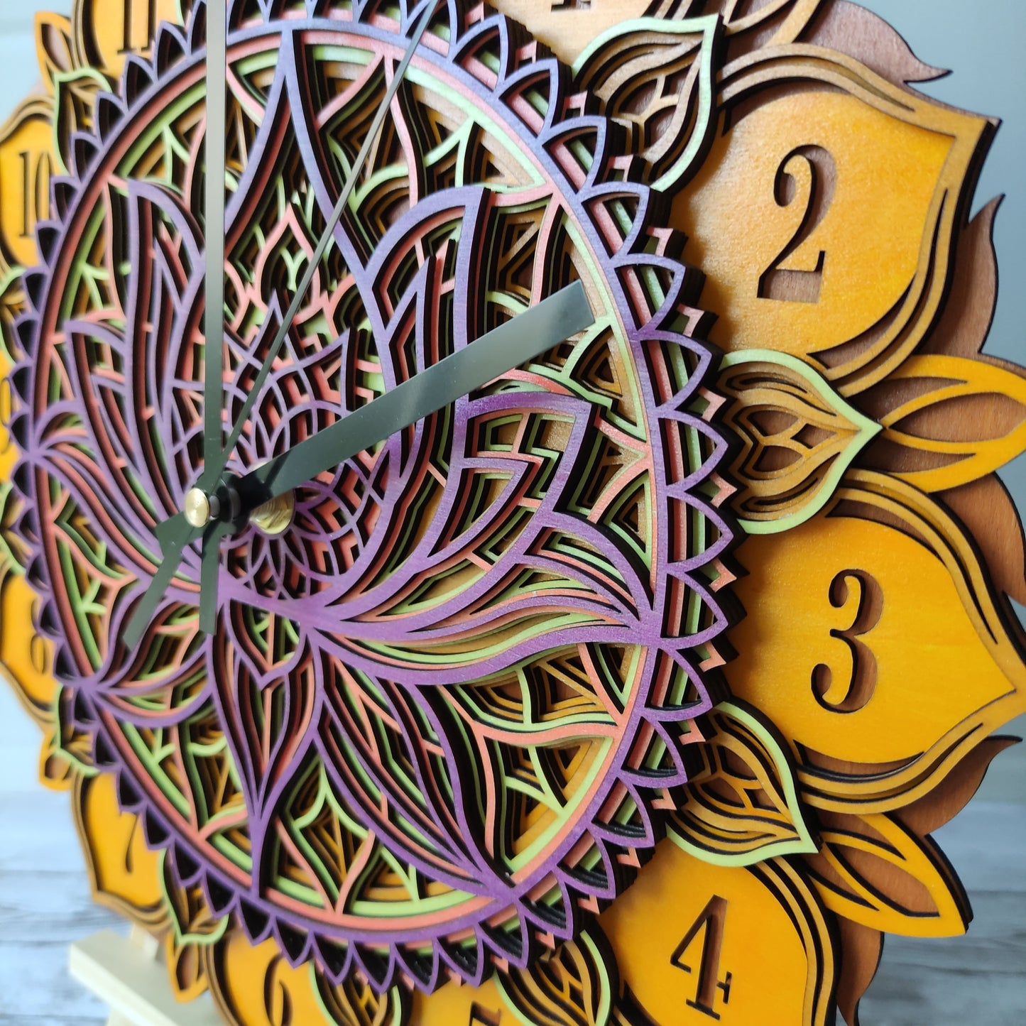 Détail des chiffres et de la structure complexe en bois de l'horloge murale mandala artisanale.