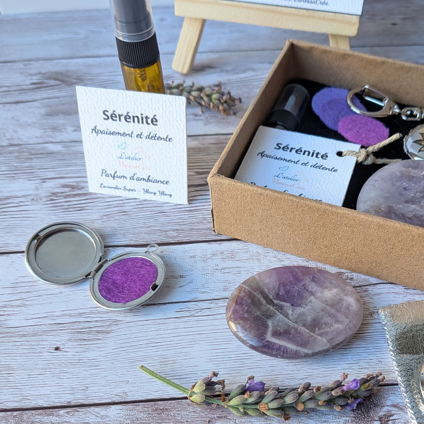 Focus sur le flacon de parfum d'ambiance bio, le médaillon porte-clés ouvert avec feutrine violette et le galet d'améthyste du coffret Sérénité.