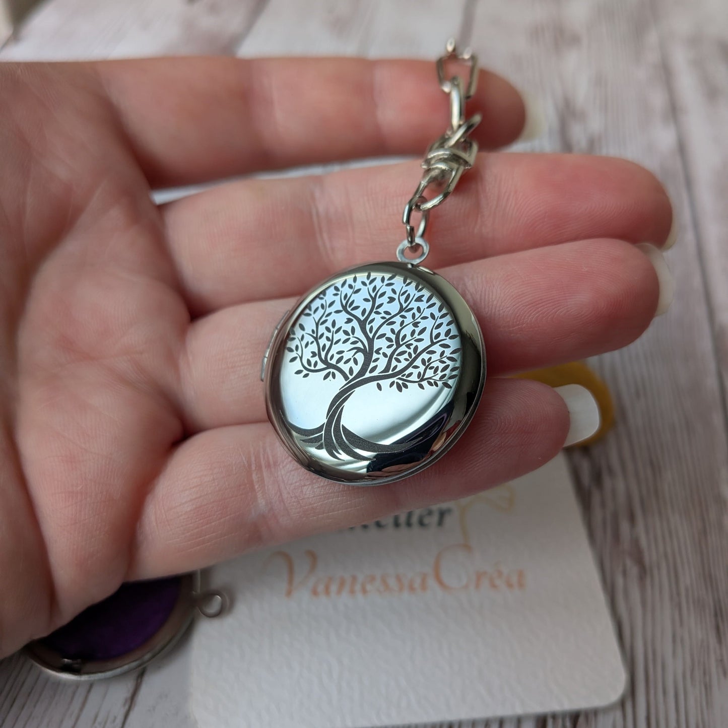 Présentation en main du porte-clés olfactif en acier inoxydable avec gravure de l'Arbre de Vie, issu du coffret Forêt Mystique.