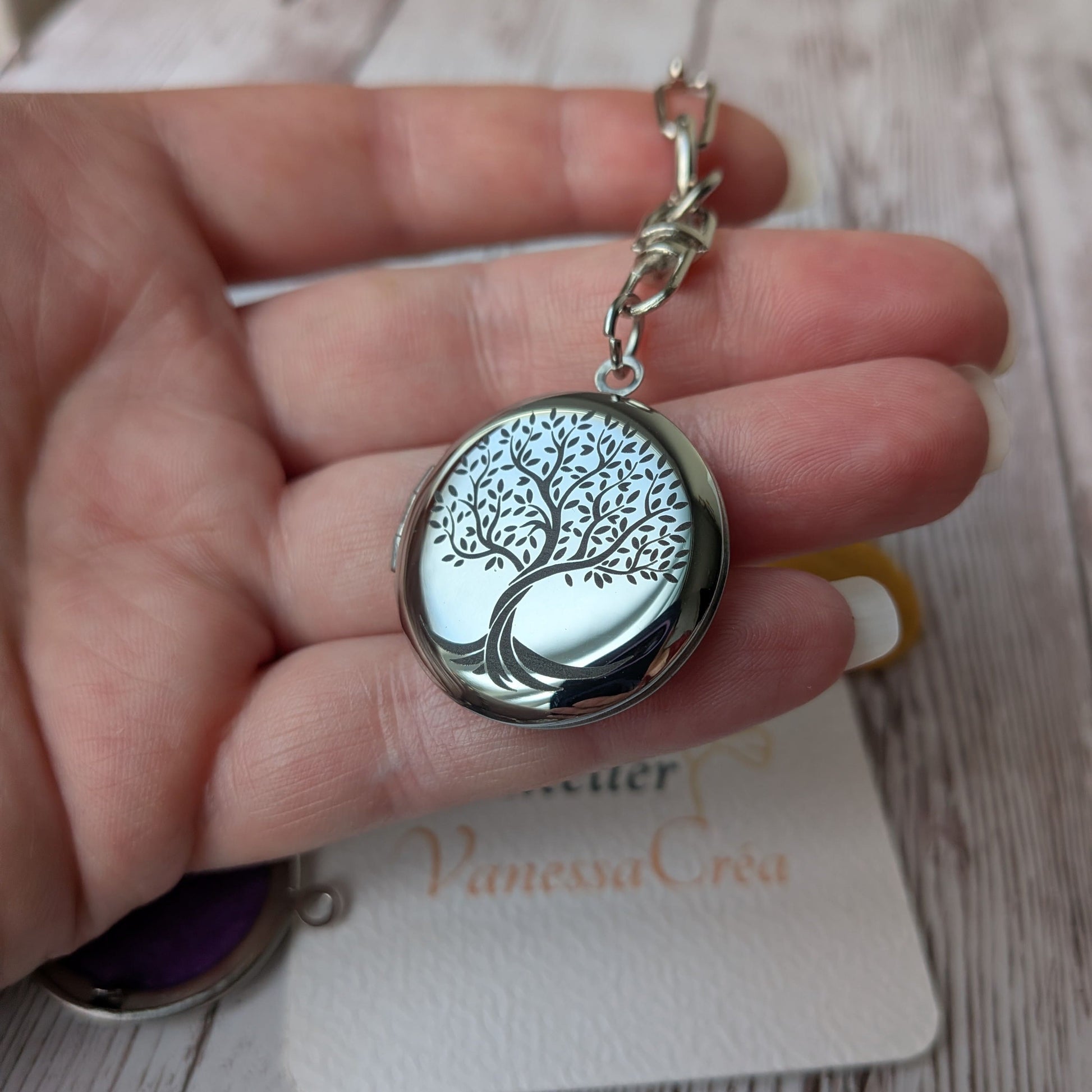 Présentation en main du porte-clés olfactif en acier inoxydable avec gravure de l'Arbre de Vie, issu du coffret Forêt Mystique.