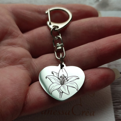 Porte-clés en forme de cœur en acier inoxydable poli miroir avec gravure laser d'une fleur de lys et texte personnalisé.