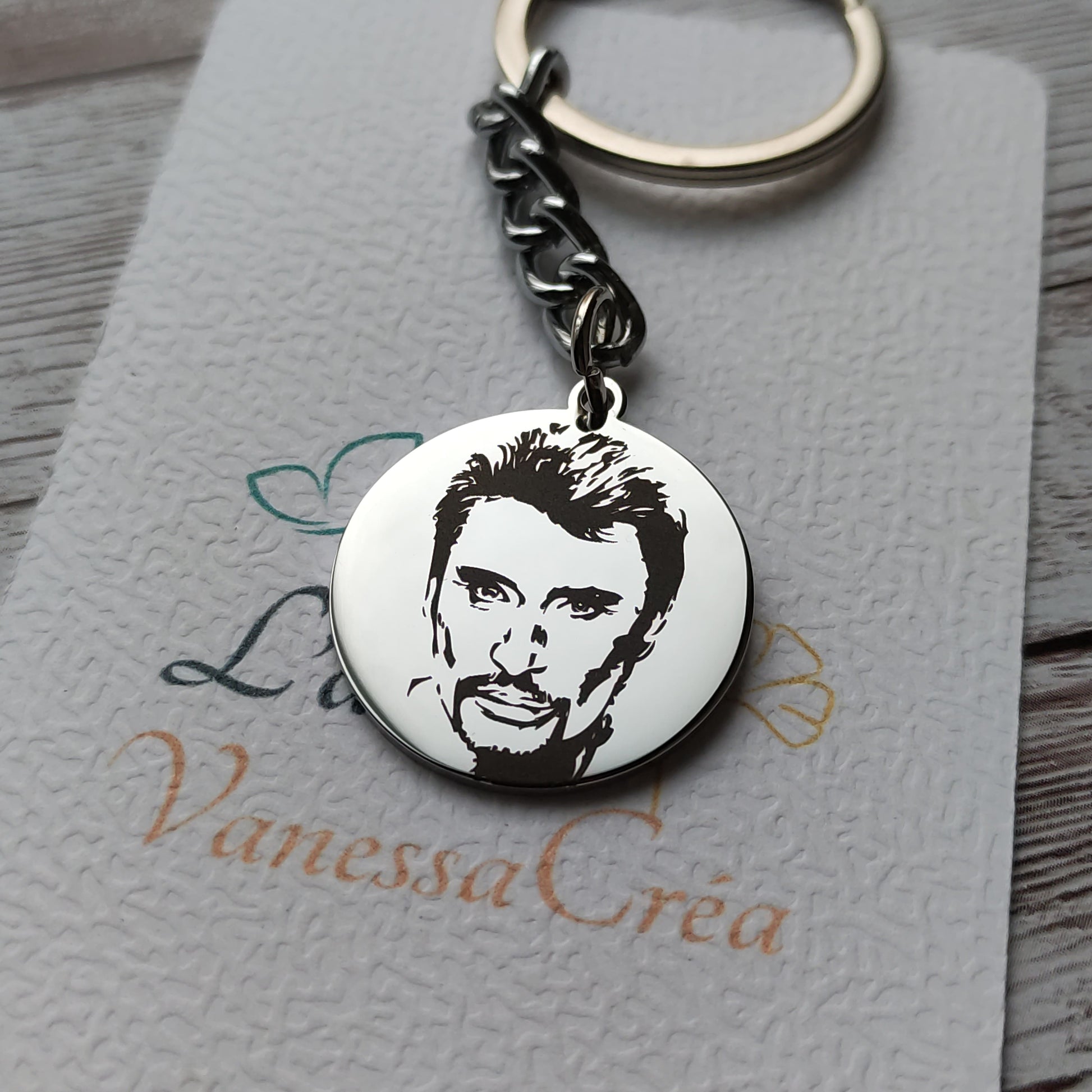 Porte-clés rond en acier inoxydable poli miroir avec gravure laser de précision de la tête de Johnny Hallyday.