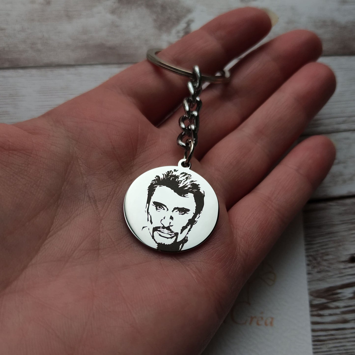 Porte-clés rond en acier inoxydable poli miroir avec gravure laser de précision de la tête de Johnny Hallyday.