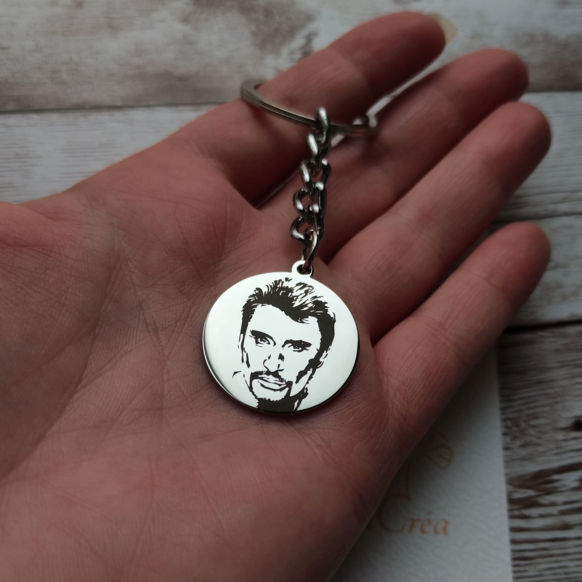 Porte-clés rond en acier inoxydable poli miroir avec gravure laser de précision de la tête de Johnny Hallyday.