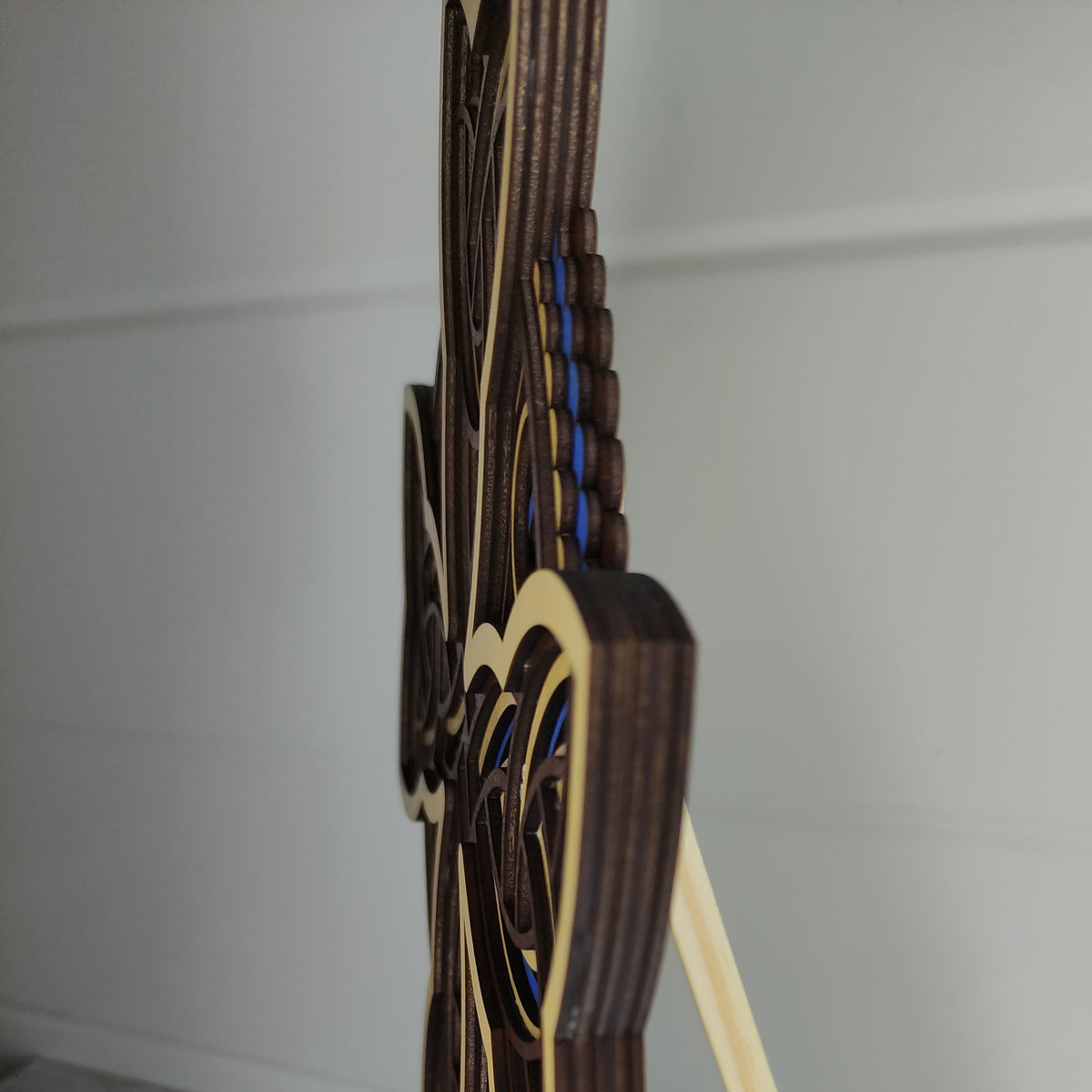 Vue de profil montrant l'épaisseur et le relief des 5 couches de bois de la croix celtique artisanale.