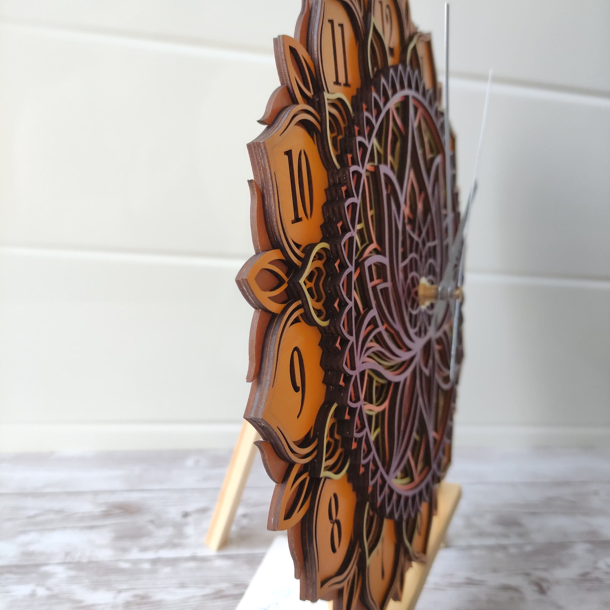 Vue de profil montrant la superposition des 7 couches de bois de tilleul créant un relief unique sur l'horloge mandala.